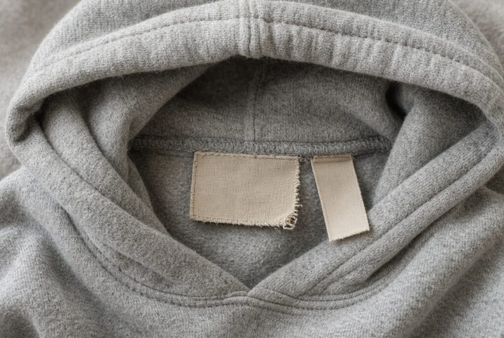 Inside collar of a hoodie with a woven neck label and a separate care label